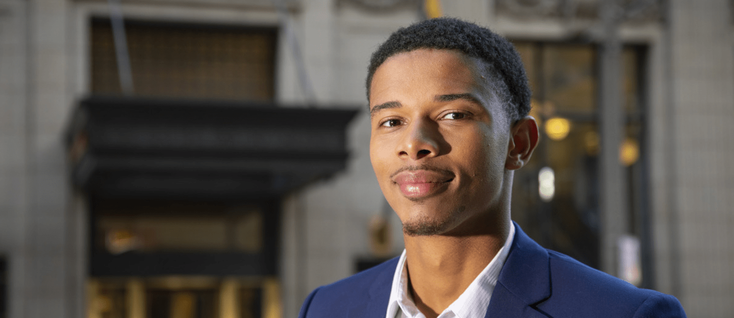 Black male student standing in front of a building.