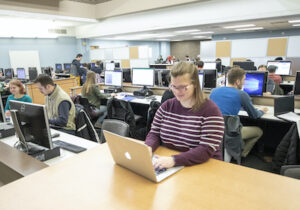学生在计算机实验室和其他大学生在后台
