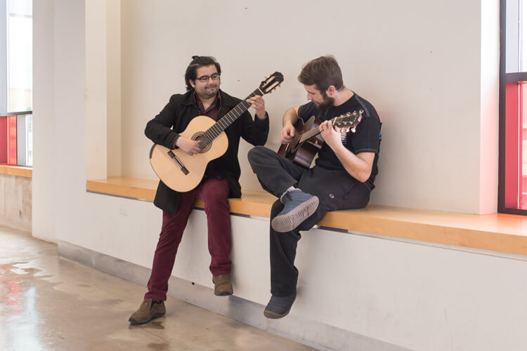 两个学生在走廊上弹吉他。