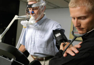 戴着氧气面罩用听诊器测量跑步机上男子的心跳