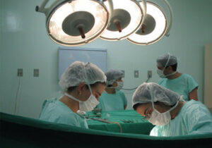 手术室里有四名医生穿着手术服和口罩